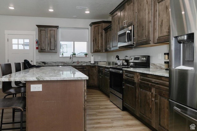 356 W Rendezvous Way, Garden City, UT 84028 - kitchen featuring a breakfast bar area, a center island, light hardwood / wood-style floors, stainless steel appliances, and light stone countertops