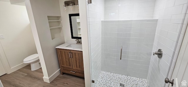 bathroom with hardwood / wood-style flooring, vanity, toilet, a shower with door, and built in shelves