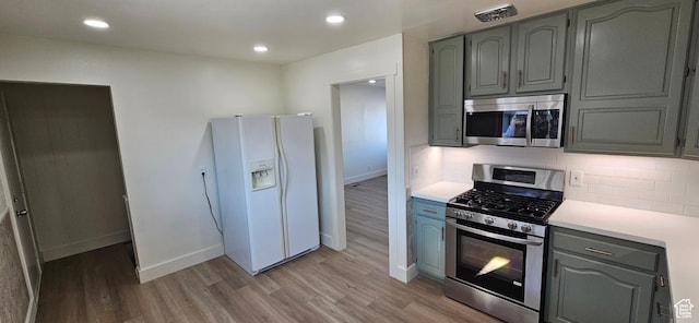 kitchen with stainless steel appliances, light hardwood / wood-style floors, and backsplash