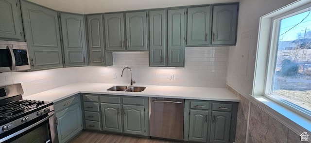 kitchen with appliances with stainless steel finishes, sink, light hardwood / wood-style flooring, and a wealth of natural light