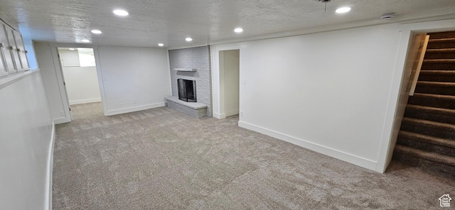 basement with light colored carpet, a fireplace, and a textured ceiling