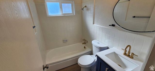 full bathroom featuring vanity, toilet, tiled shower / bath combo, and tile walls