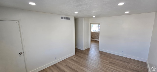 unfurnished room featuring light hardwood / wood-style flooring and a textured ceiling