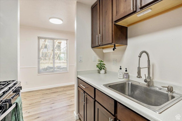 435 E Creekside Cir S Unit A, Salt Lake City, UT 84107 - kitchen featuring a sink, gas range, dark brown cabinets, light wood finished floors, and light countertops