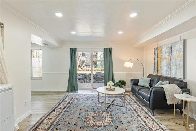 living area featuring light wood-style floors, crown molding, and baseboards