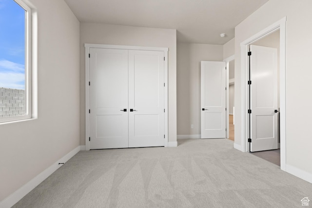 unfurnished bedroom featuring a closet, carpet flooring, multiple windows, and baseboards