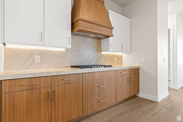 kitchen featuring premium range hood, stainless steel gas stovetop, and light countertops