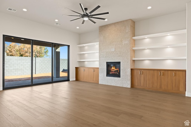 unfurnished living room with a fireplace, light wood-style floors, and visible vents