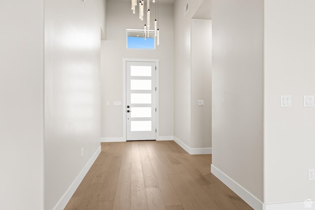 foyer featuring visible vents, wood-type flooring, a high ceiling, and baseboards