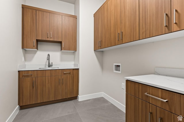 laundry room with cabinet space, hookup for a washing machine, baseboards, and a sink