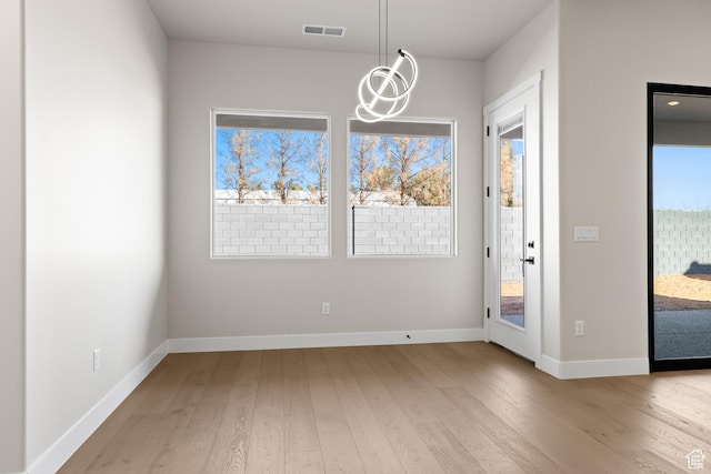 unfurnished dining area featuring visible vents, baseboards, and hardwood / wood-style floors