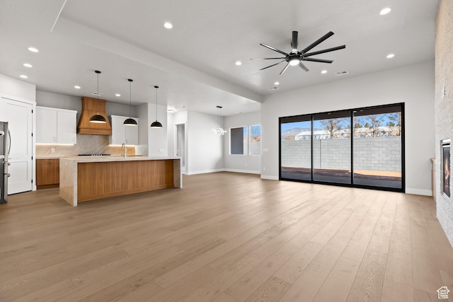 kitchen with light wood finished floors, open floor plan, light countertops, and custom range hood