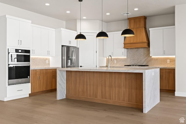 kitchen with visible vents, an island with sink, a sink, light wood-style floors, and stainless steel fridge with ice dispenser
