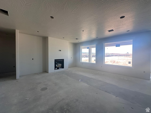 3997 W 1500 S, Hurricane, UT 84737 - unfurnished living room featuring a textured ceiling, a fireplace, and unfinished concrete floors