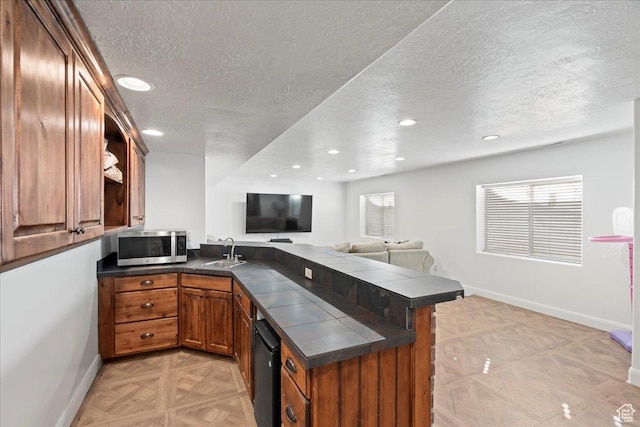 kitchen with a healthy amount of sunlight, kitchen peninsula, sink, and light parquet floors