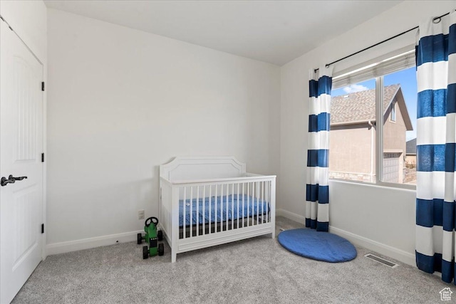 carpeted bedroom featuring a nursery area