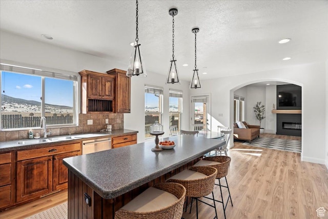 kitchen featuring sink, stainless steel dishwasher, a kitchen breakfast bar, a kitchen island, and decorative backsplash