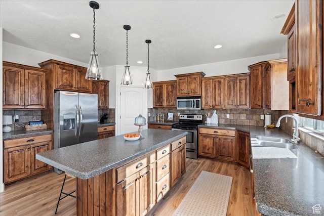 kitchen featuring sink, a center island, light hardwood / wood-style flooring, pendant lighting, and stainless steel appliances