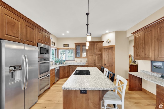 9284 E Tree Top Cir Unit 856, Heber City, UT 84032 - kitchen with appliances with stainless steel finishes, brown cabinets, a kitchen breakfast bar, light wood-style flooring, and a kitchen island