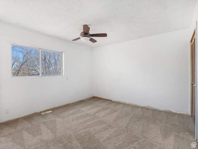 unfurnished room with ceiling fan, light carpet, and a textured ceiling