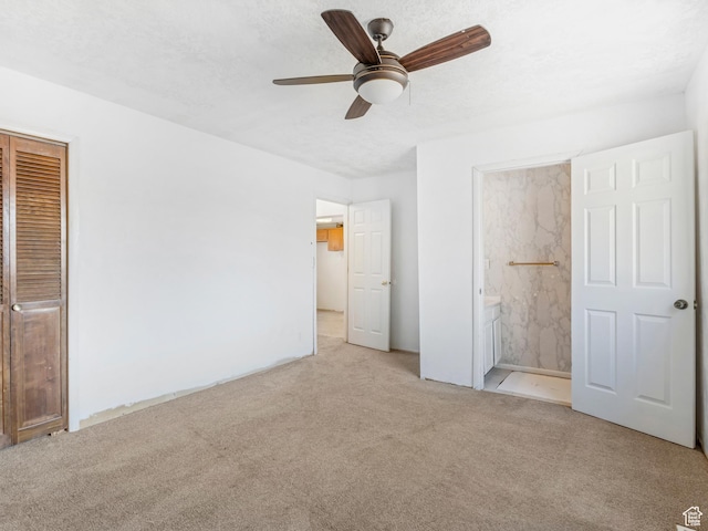 unfurnished bedroom with ceiling fan, ensuite bath, light carpet, and a textured ceiling