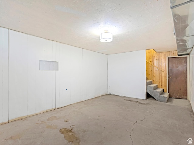 basement with wooden walls and a textured ceiling