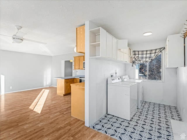 clothes washing area with ceiling fan, washer and dryer, a textured ceiling, and light wood-type flooring