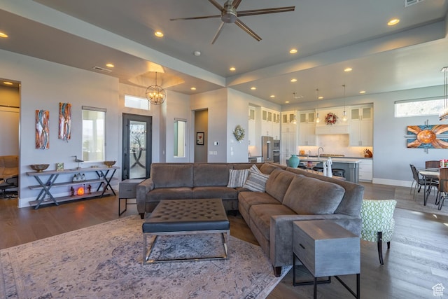 living room with sink, ceiling fan with notable chandelier, and wood-type flooring