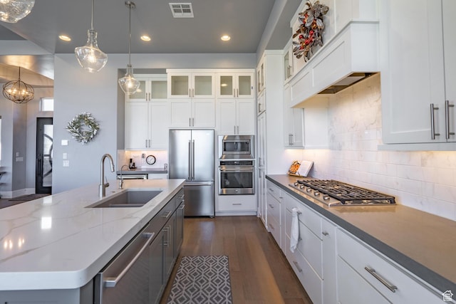 kitchen with white cabinetry, built in appliances, decorative light fixtures, and sink