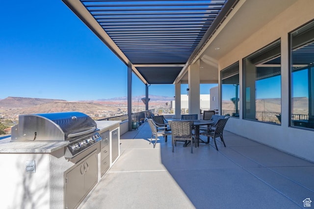 view of patio / terrace featuring a grill, exterior kitchen, and a mountain view
