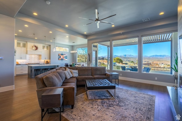living room featuring a mountain view, dark hardwood / wood-style floors, and ceiling fan with notable chandelier