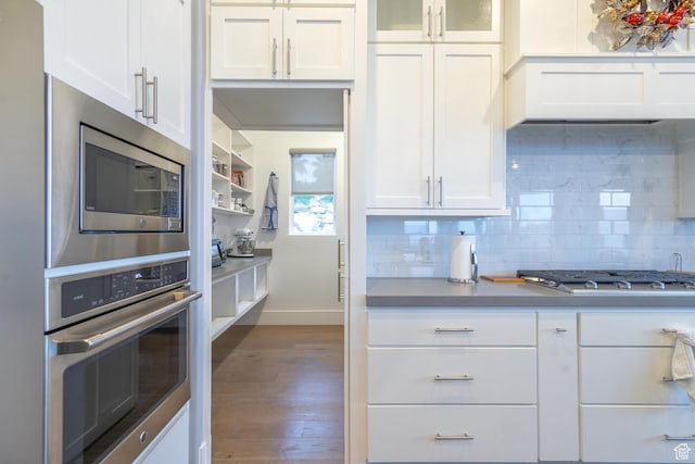kitchen with tasteful backsplash, white cabinetry, appliances with stainless steel finishes, and dark wood-type flooring