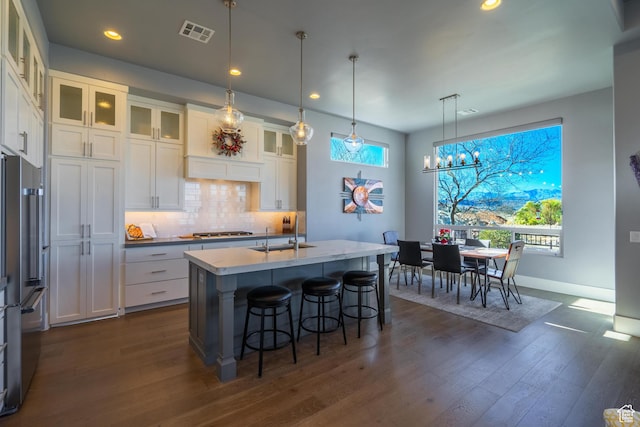 kitchen with sink, decorative light fixtures, appliances with stainless steel finishes, a kitchen island with sink, and white cabinets