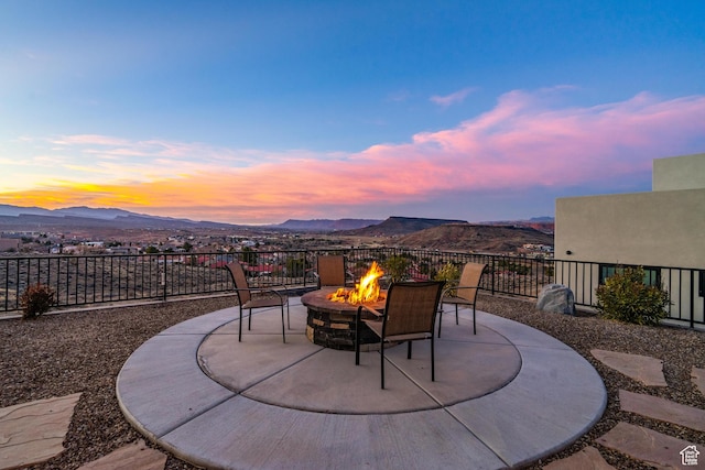 patio terrace at dusk featuring a mountain view and an outdoor fire pit