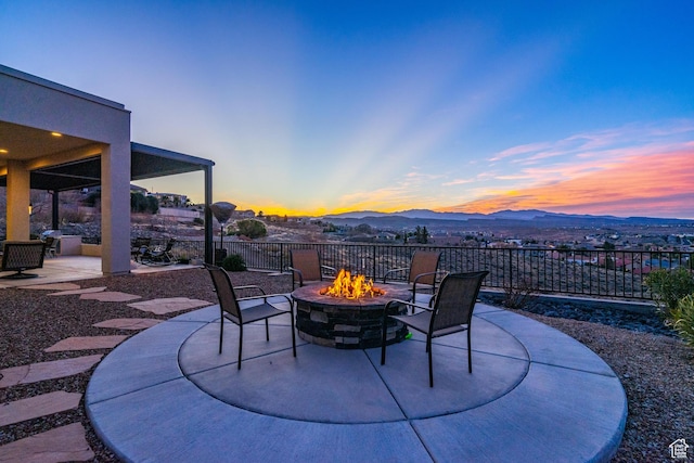 patio terrace at dusk featuring a mountain view and a fire pit