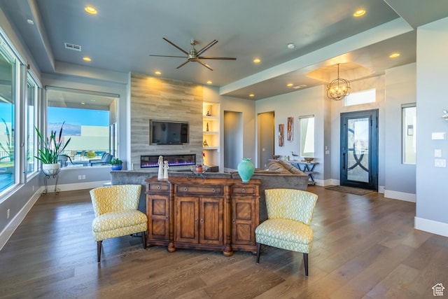 interior space featuring dark hardwood / wood-style floors, a fireplace, built in features, and a notable chandelier