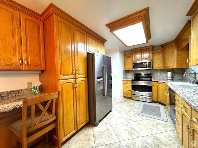 500 W Clark St S, Grantsville, UT 84029 - kitchen featuring light tile patterned flooring, a sink, brown cabinetry, stainless steel appliances, and decorative backsplash