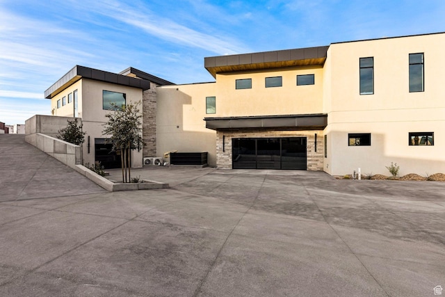 20 N Cliffside Dr, Washington, UT 84780 - view of front of house with stone siding, concrete driveway, an attached garage, and stucco siding