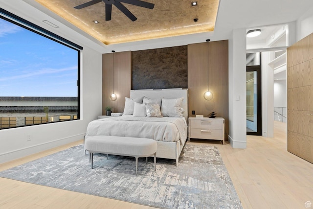 20 N Cliffside Dr, Washington, UT 84780 - bedroom with light wood finished floors, visible vents, baseboards, a raised ceiling, and ceiling fan