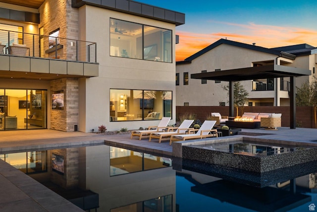 20 N Cliffside Dr, Washington, UT 84780 - back of house at dusk featuring a patio, an outdoor fire pit, a balcony, stone siding, and stucco siding