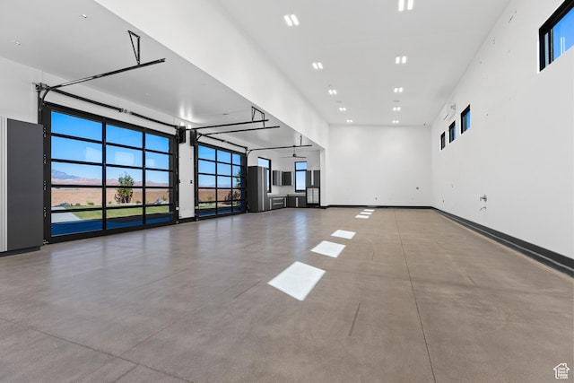 20 N Cliffside Dr, Washington, UT 84780 - unfurnished living room featuring a towering ceiling, baseboards, and concrete flooring