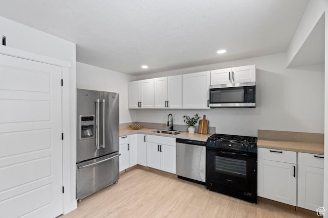 kitchen featuring white cabinetry, sink, stainless steel appliances, and light hardwood / wood-style floors