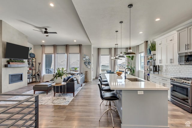 14203 S Brook Heights Cir W, Herriman, UT 84096 - kitchen with sink, appliances with stainless steel finishes, a kitchen breakfast bar, an island with sink, and backsplash