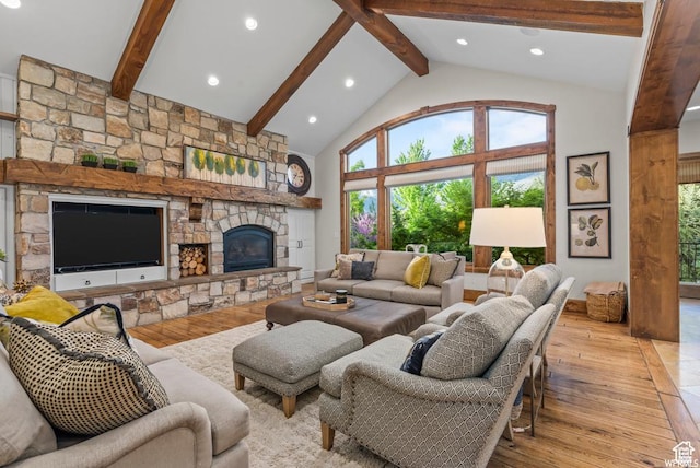 living room with beamed ceiling, a stone fireplace, high vaulted ceiling, and light hardwood / wood-style flooring