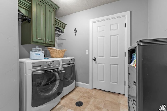laundry room featuring washing machine and dryer, cabinets, and a textured ceiling