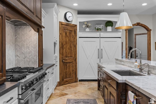 kitchen with dark brown cabinetry, sink, light stone counters, double oven range, and pendant lighting