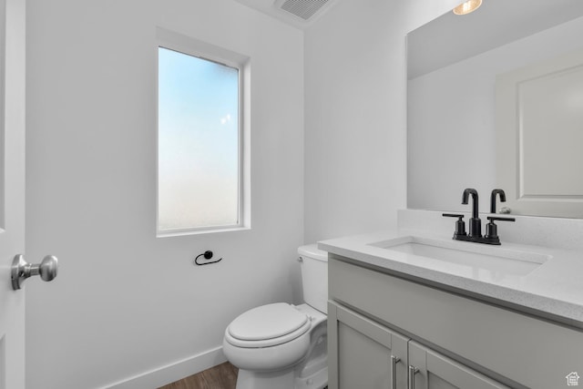 bathroom with hardwood / wood-style flooring, vanity, and toilet