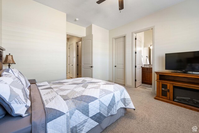bedroom featuring light colored carpet, ceiling fan, and ensuite bath