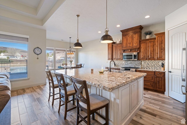 1512 Cholla Dr, Toquerville, UT 84774 - kitchen featuring stainless steel microwave, light wood-type flooring, brown cabinets, light stone counters, and recessed lighting