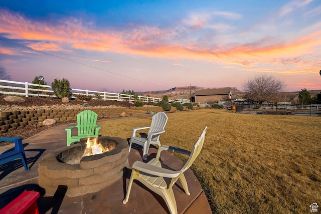 patio terrace at dusk with a lawn and an outdoor fire pit